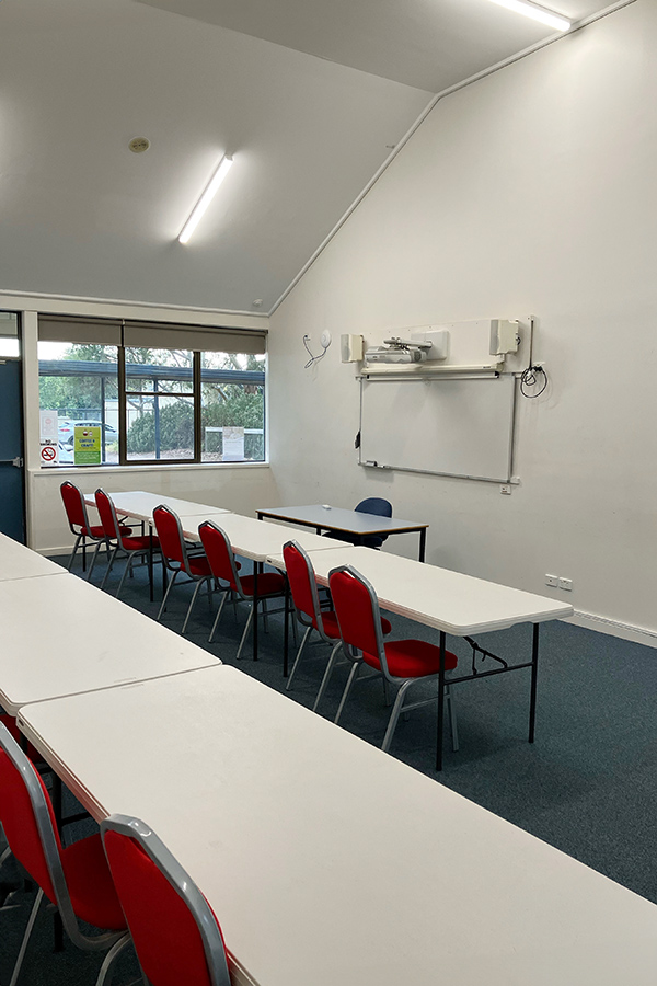 Large classroom set equipped with tables, chairs and whiteboard