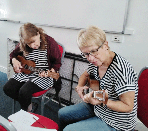 Two woman playing Ukulele next to eachother