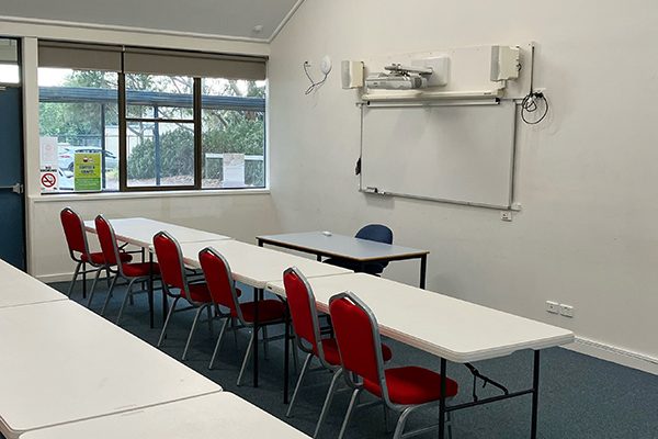 Large classroom set equipped with tables, chairs and whiteboard