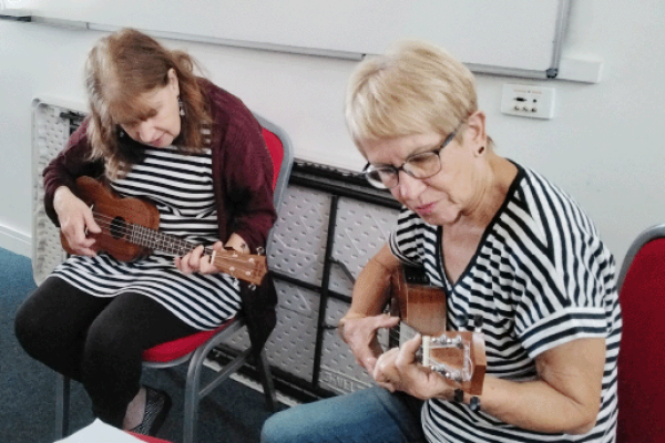 Two woman playing Ukulele next to eachother