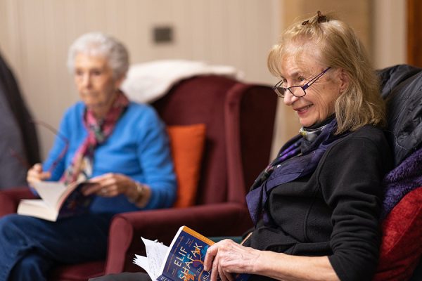 Two women with open books sitting together in book club